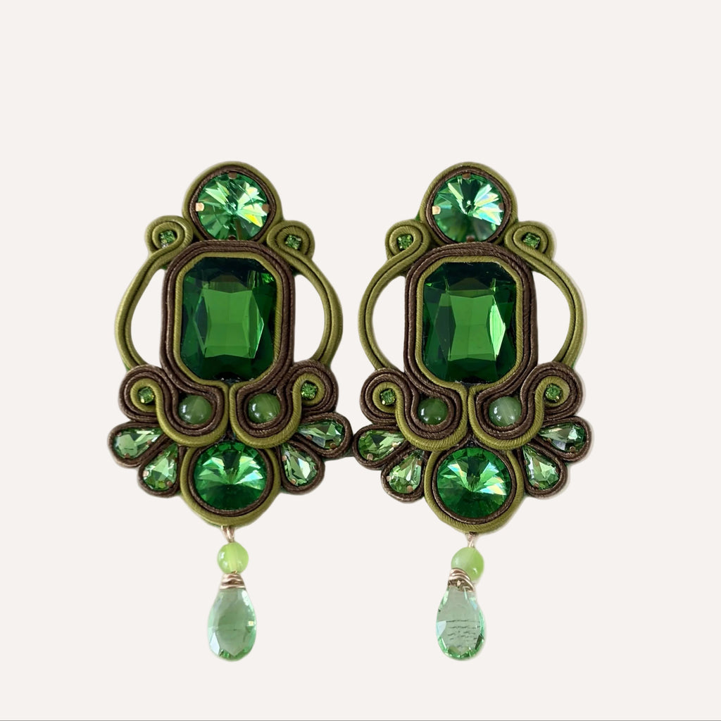 Pair of green gemstone earrings on a beige background